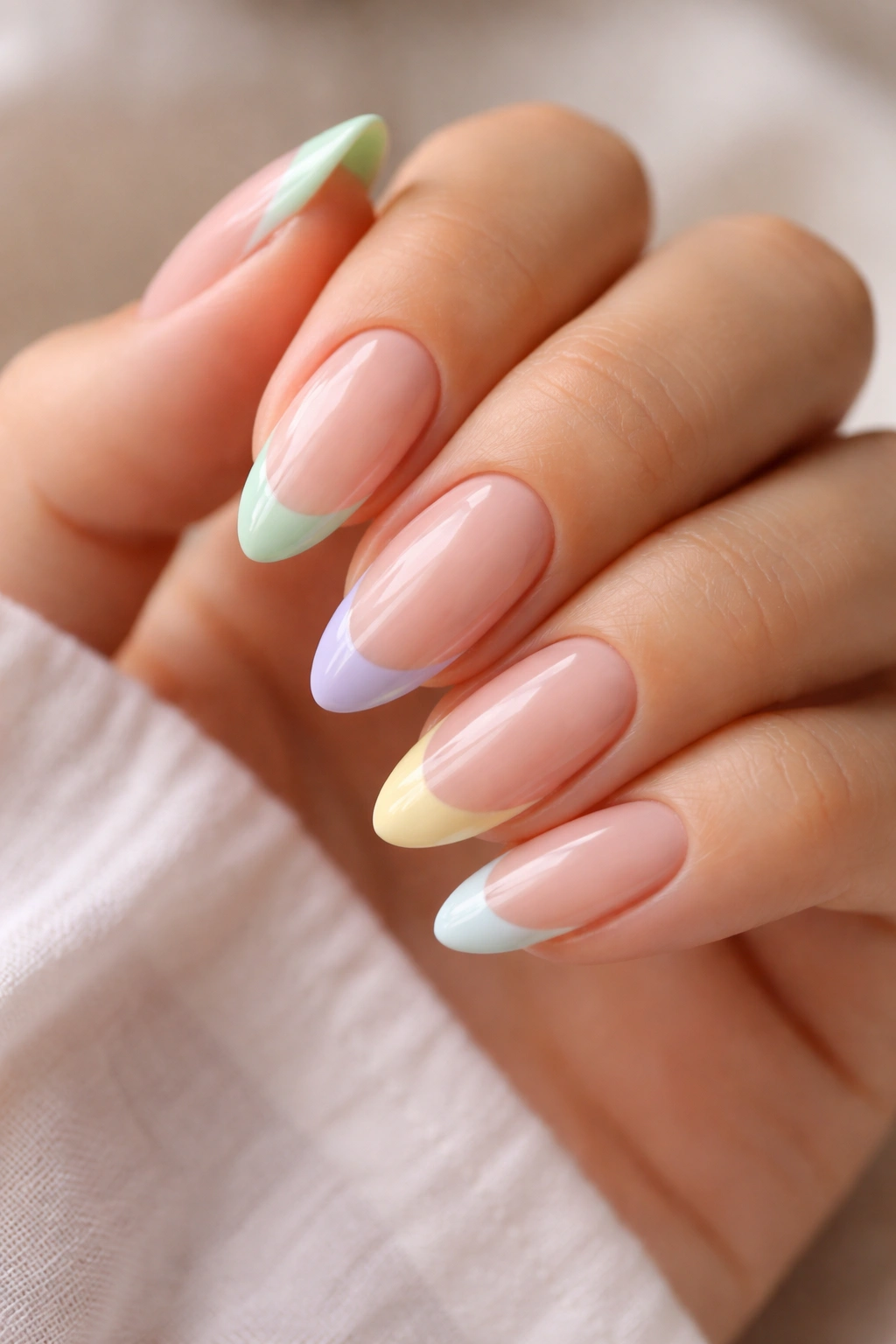 Almond nails with mixed pastel French tips on a sheer nude base