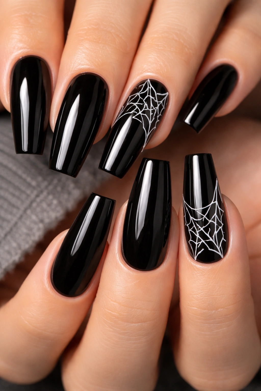 Glossy black coffin nails with white spiderweb lines on accent nails.