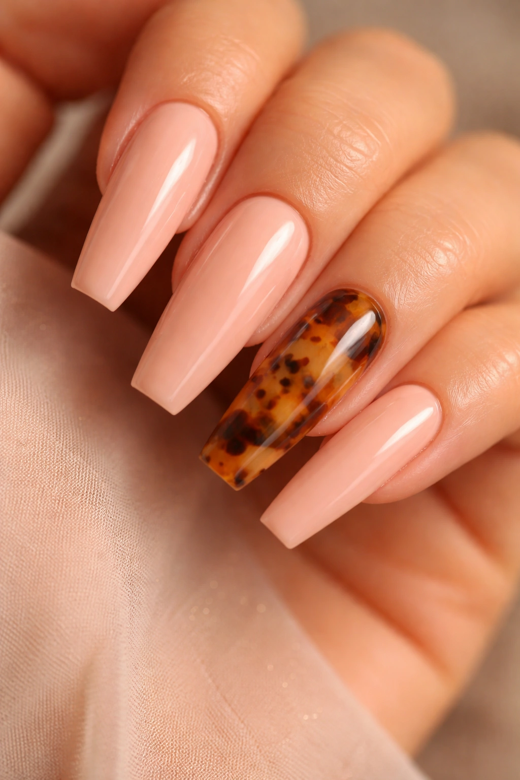 Close-up of peach-pink coffin nails with tortoiseshell accent nails