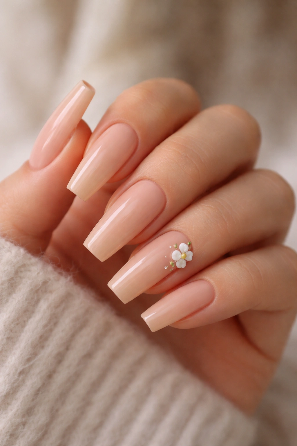 Peachy nude coffin nails with tiny embedded flower charms.