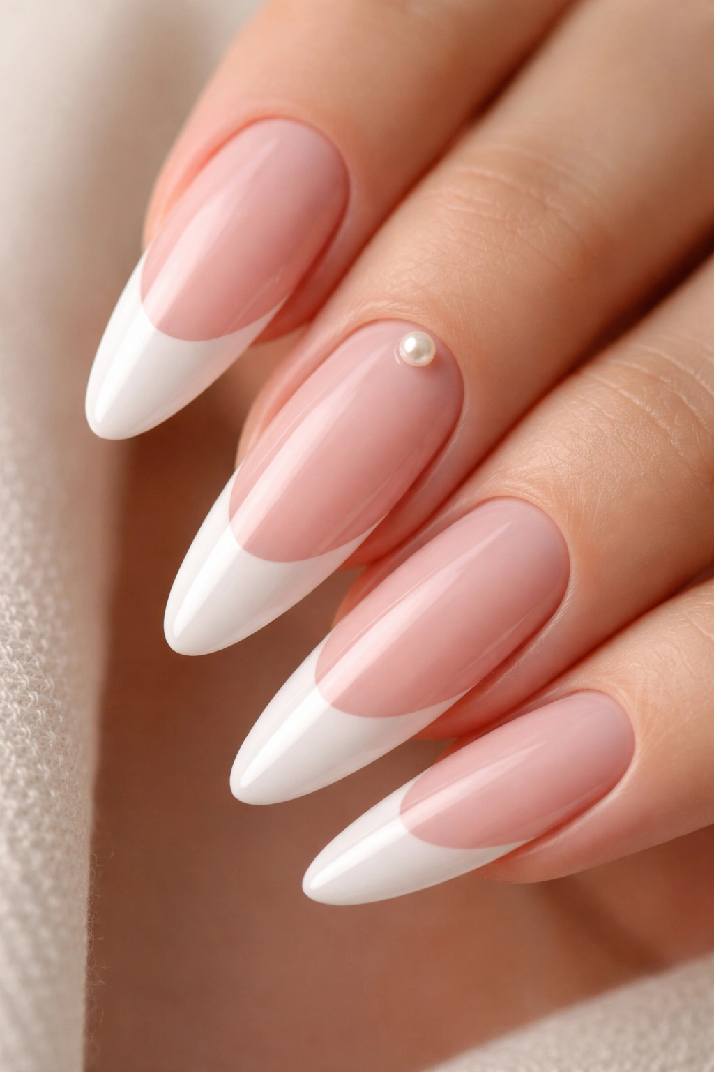 Close-up of long almond nails with a single pearl accent near the cuticle on one nail with a French tip.