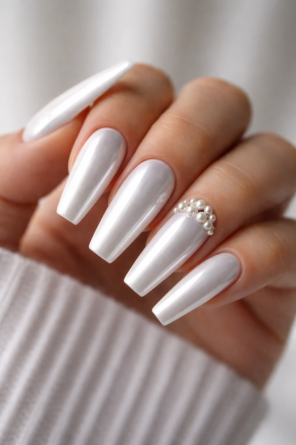 White chrome coffin nails with one pearl-studded accent nail