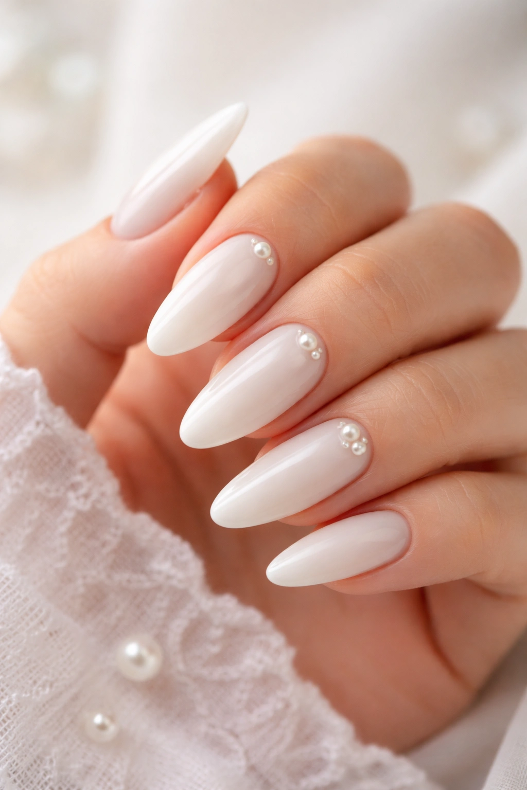 Close-up of almond nails with pearl accents near the cuticle