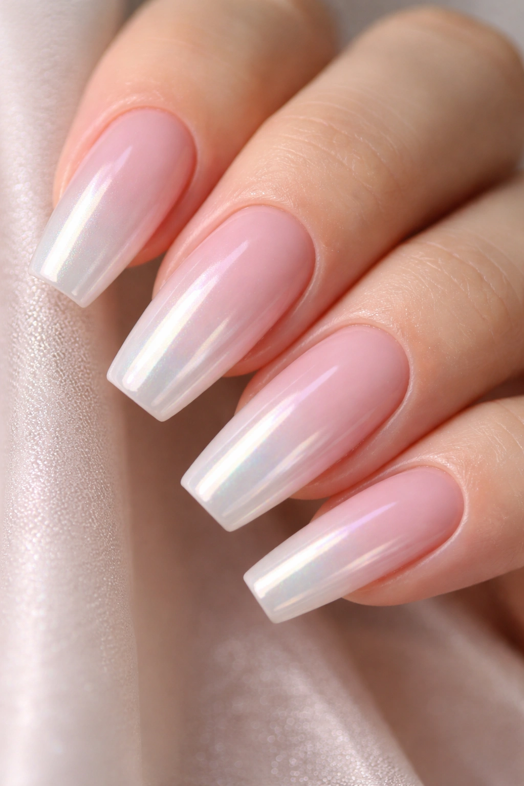 Close-up of sheer pink ombre coffin nails with pearl chrome veil, neutral backdrop