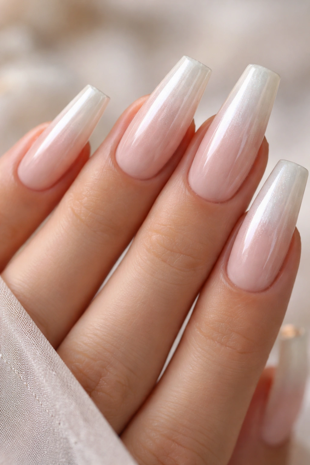 Close-up of pearl-glazed nude ombre coffin nails with milky finish