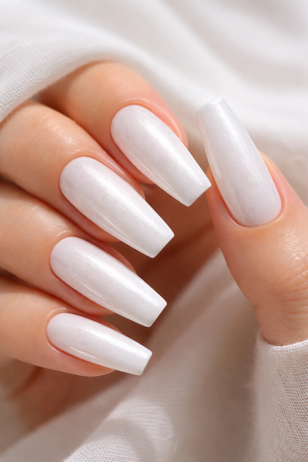 Close-up of white nails with delicate pearl shimmer and soft iridescence.