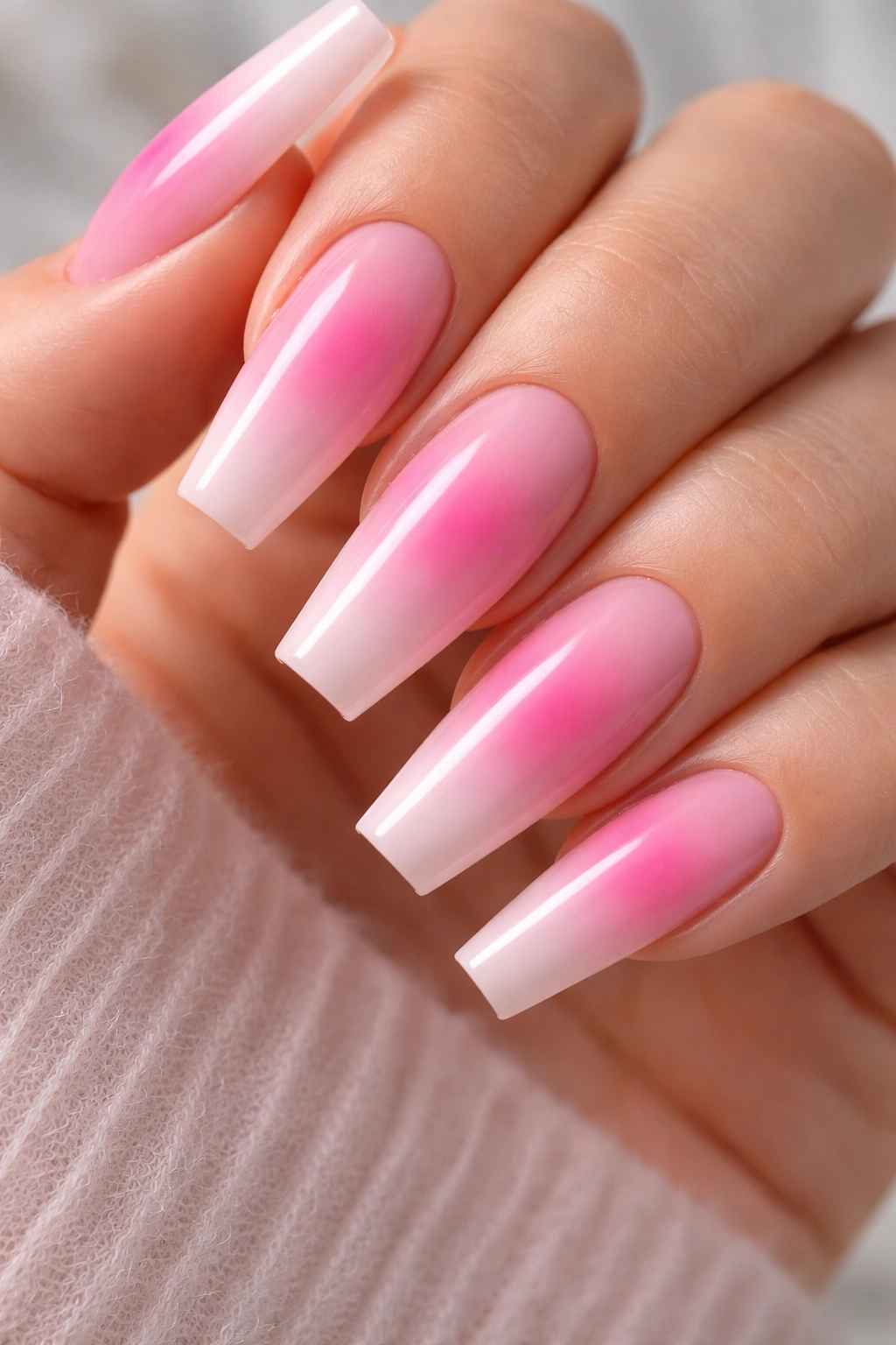 Close-up of pink aura coffin nails with blurred center on nude-pink base.