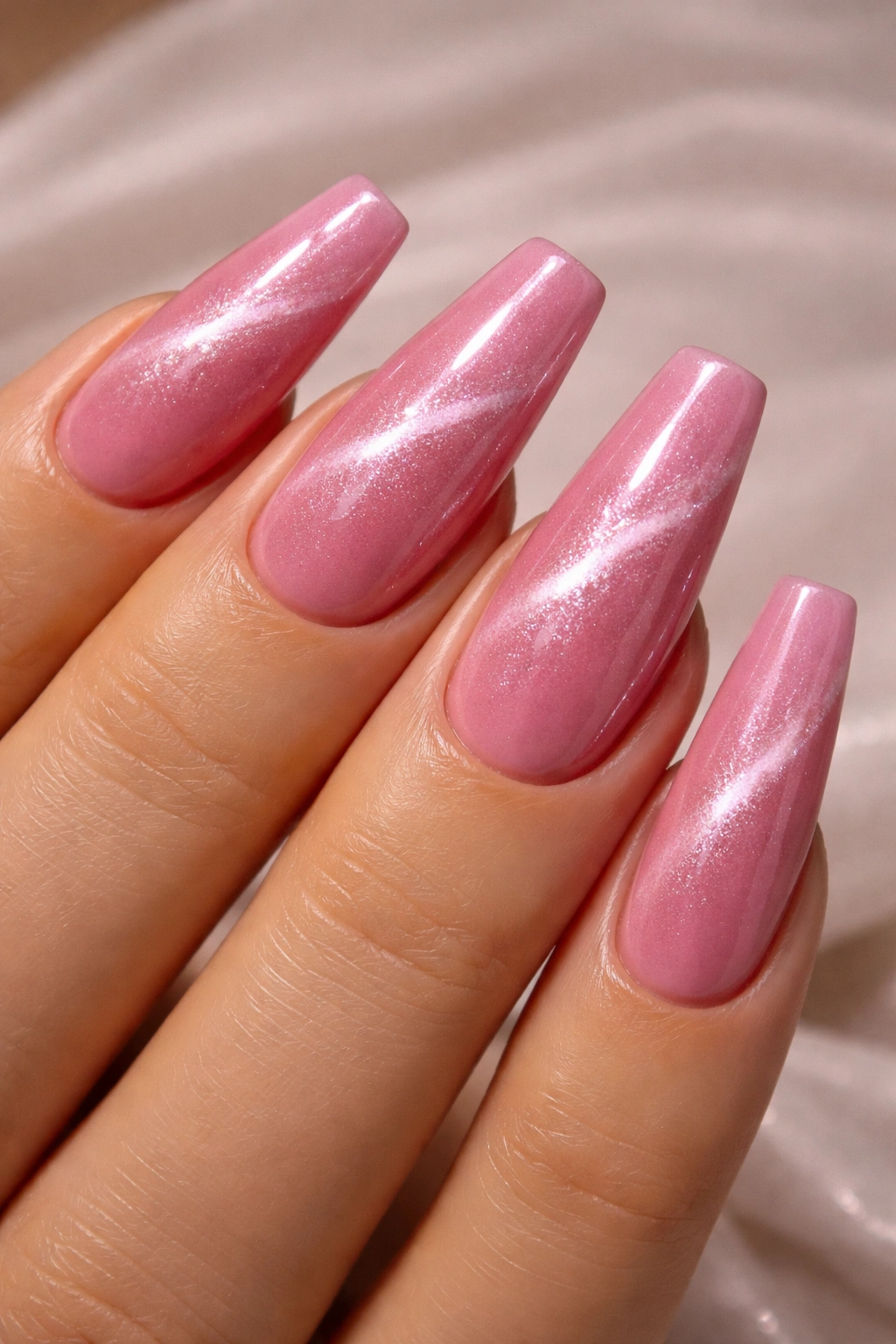 Close-up of pink cat-eye coffin nails showing diagonal shimmer stripe