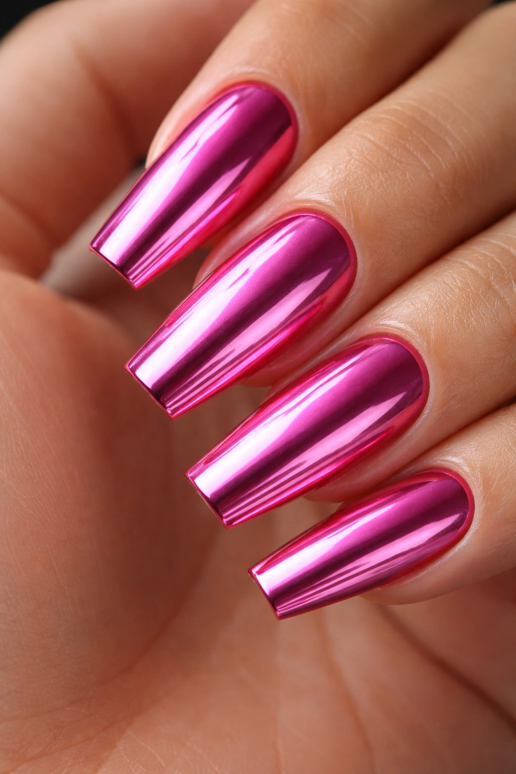Coffin nails with pink chrome mirror finish reflecting light on a plain background