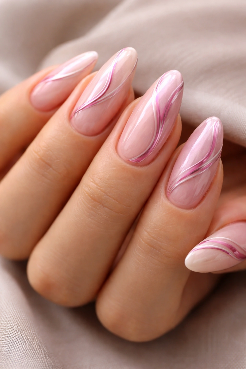 Close-up almond nails with pink chrome swirls on a nude base, soft reflective lines.