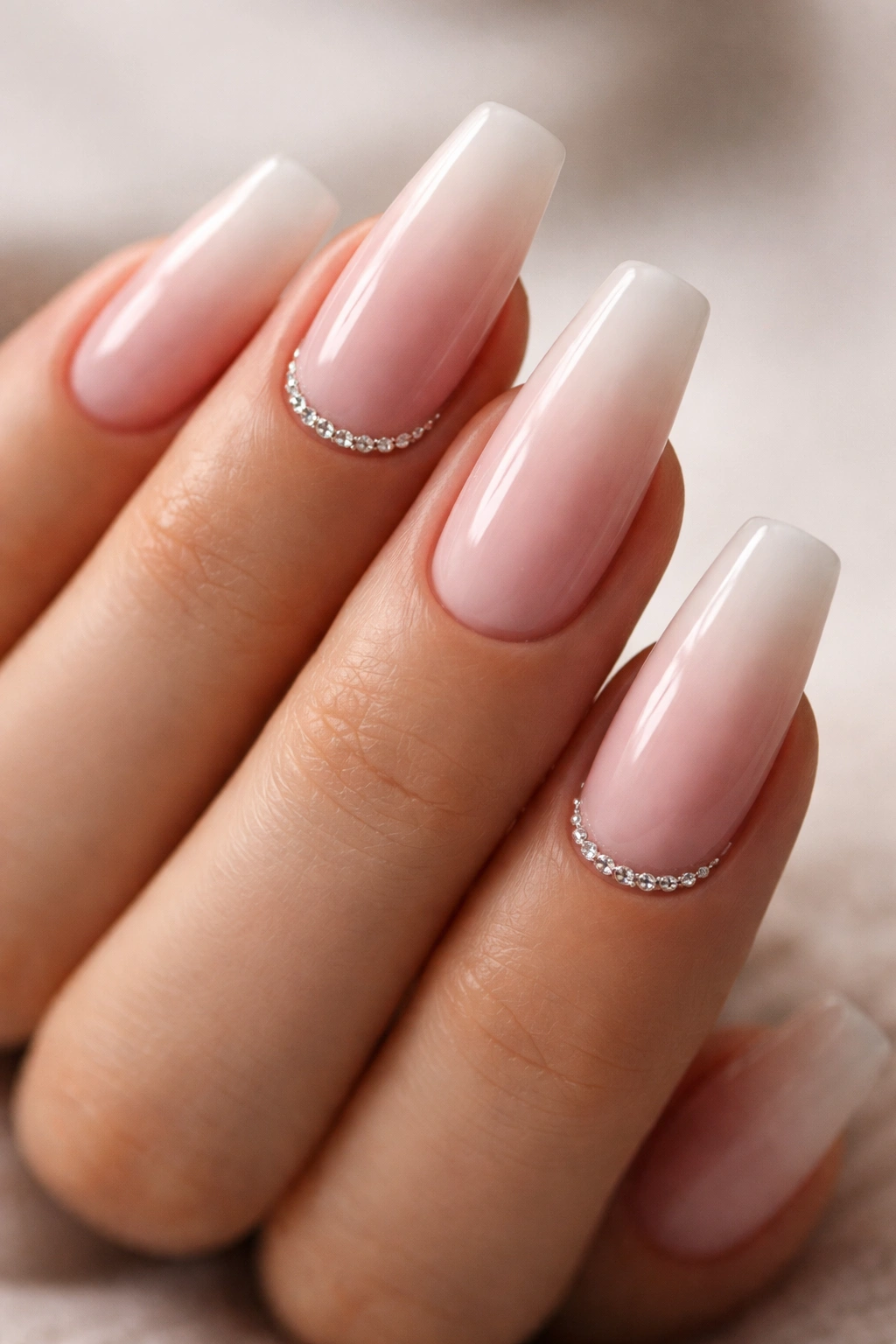 Close-up of coffin nails with pink French fade and a rhinestone cuticle line on select nails