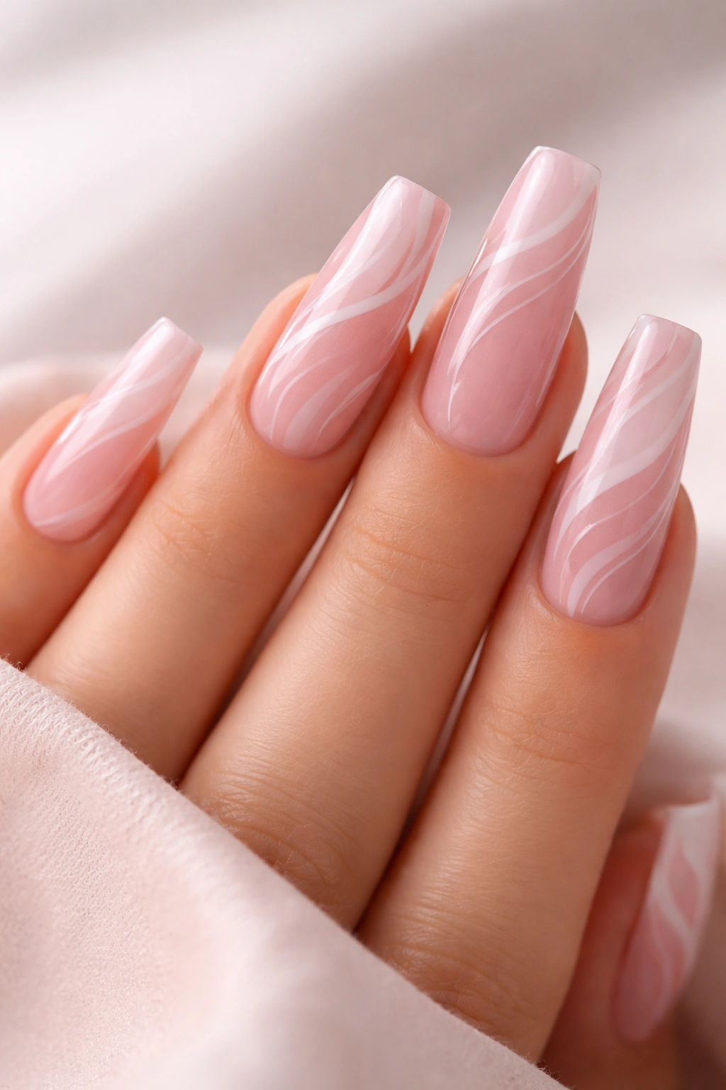 Close-up of pink swirl coffin nails with sheer base and delicate white swirls