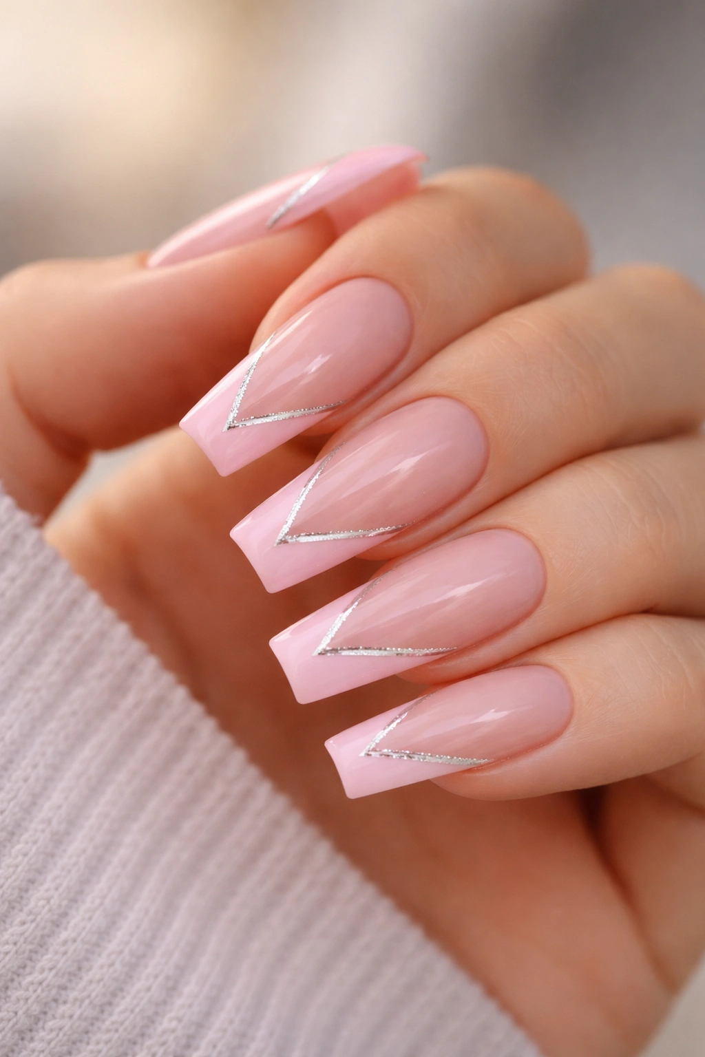 Close-up of pink V-cut tips with a fine silver divider on medium coffin nails