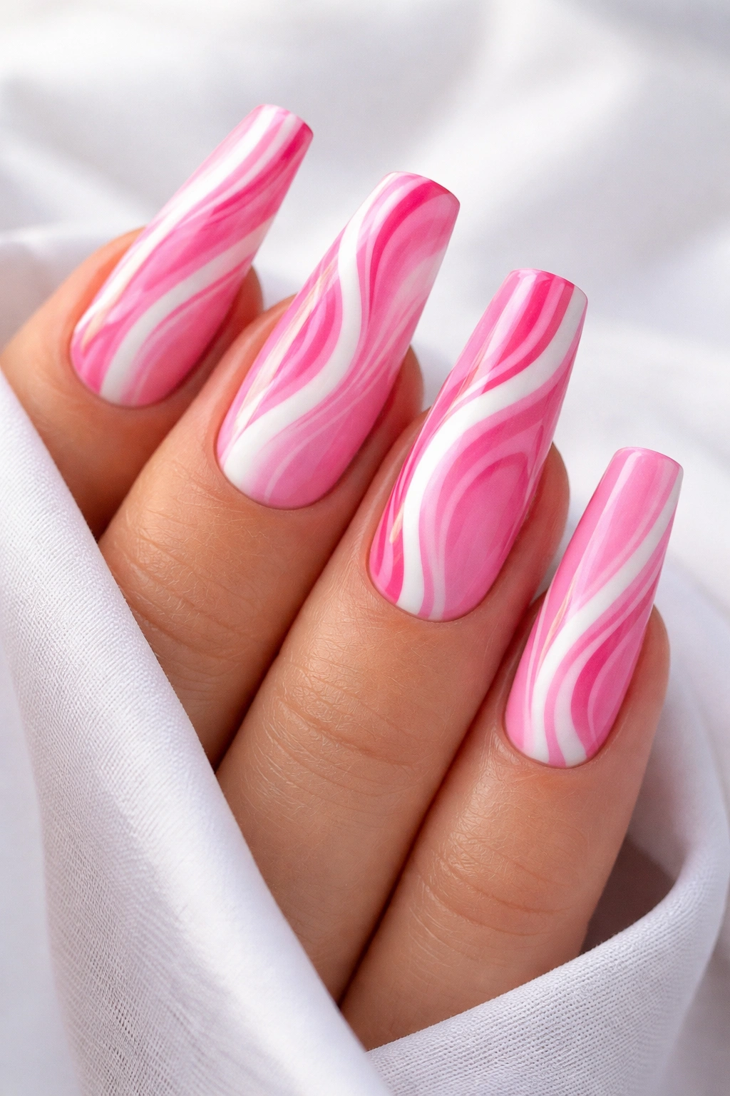 Coffin nails with pink and white swirl patterns on a clean background