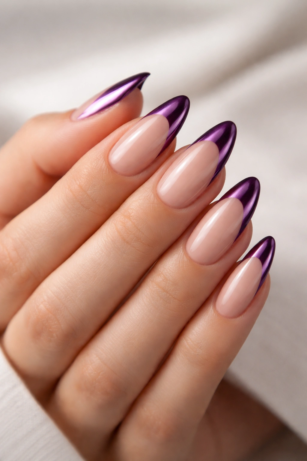 Close-up of nude almond nails with plum chrome French tips on a clean background