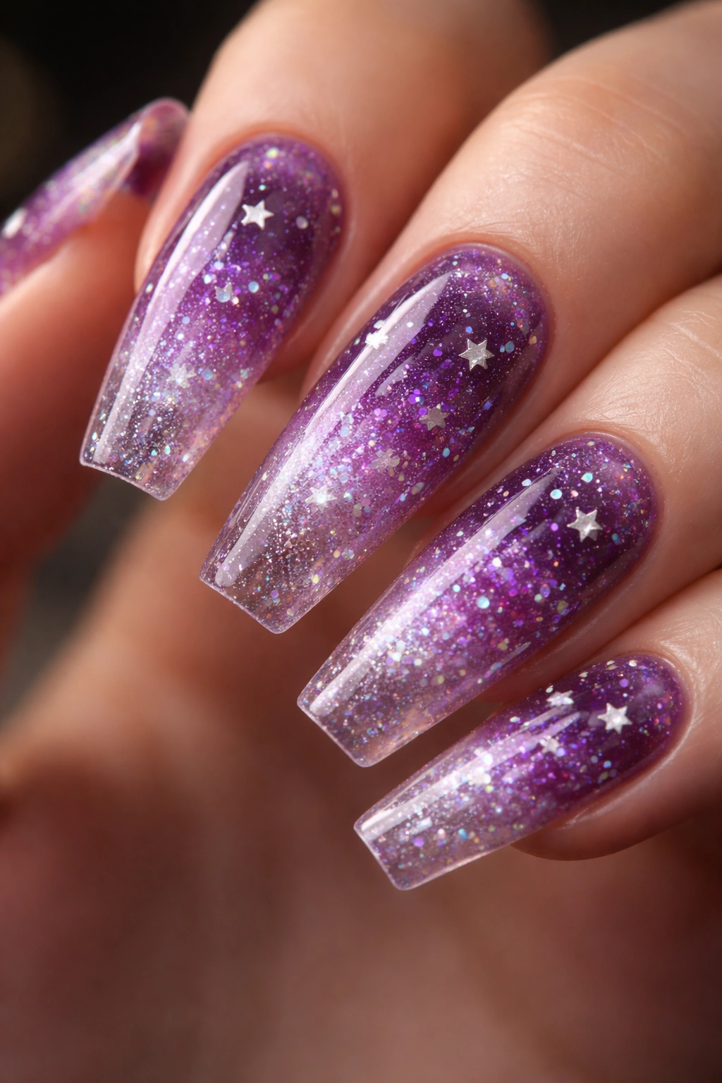 Close-up of plum jelly coffin nails with holographic dust and tiny stars