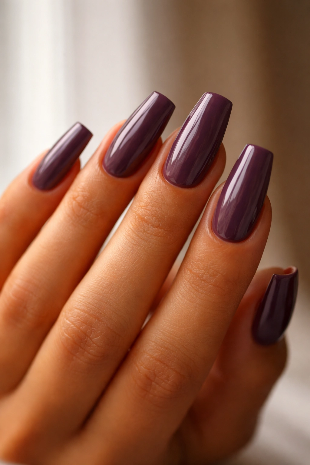 Close-up of hand with coffin nails in plum shade on medium length showing skin-tone compatibility