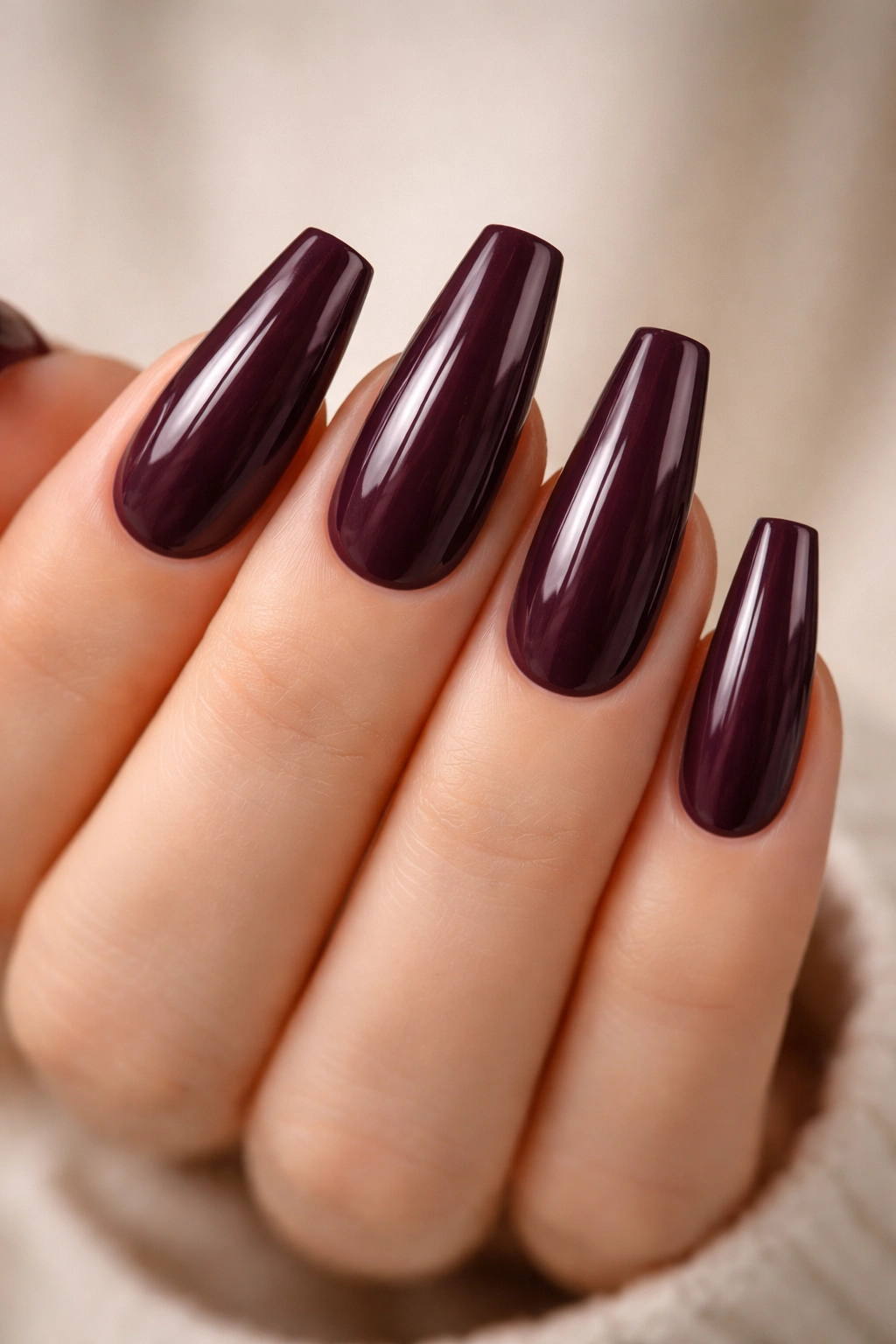 Hand with glossy plum wine coffin nails with deep purple color and glossy finish