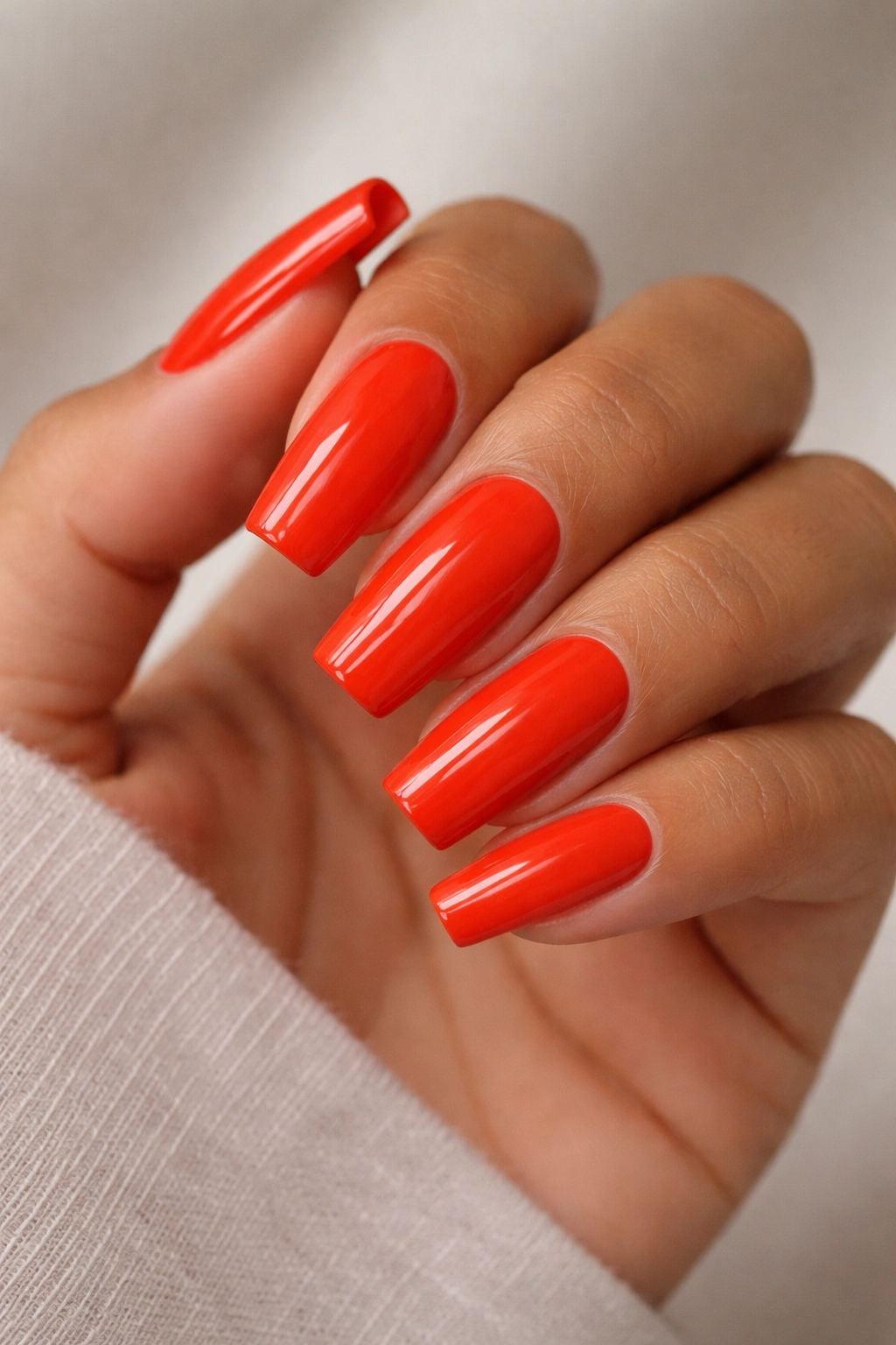 Close-up of medium coffin nails painted in bright poppy red with a glossy finish.