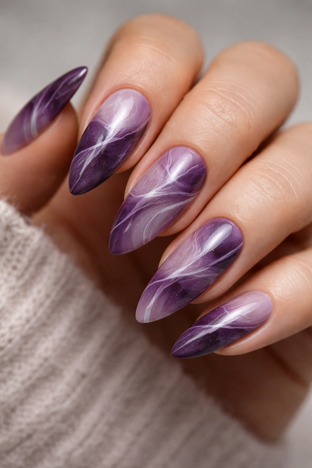 Close-up of purple marble almond nails with white veining and glossy finish