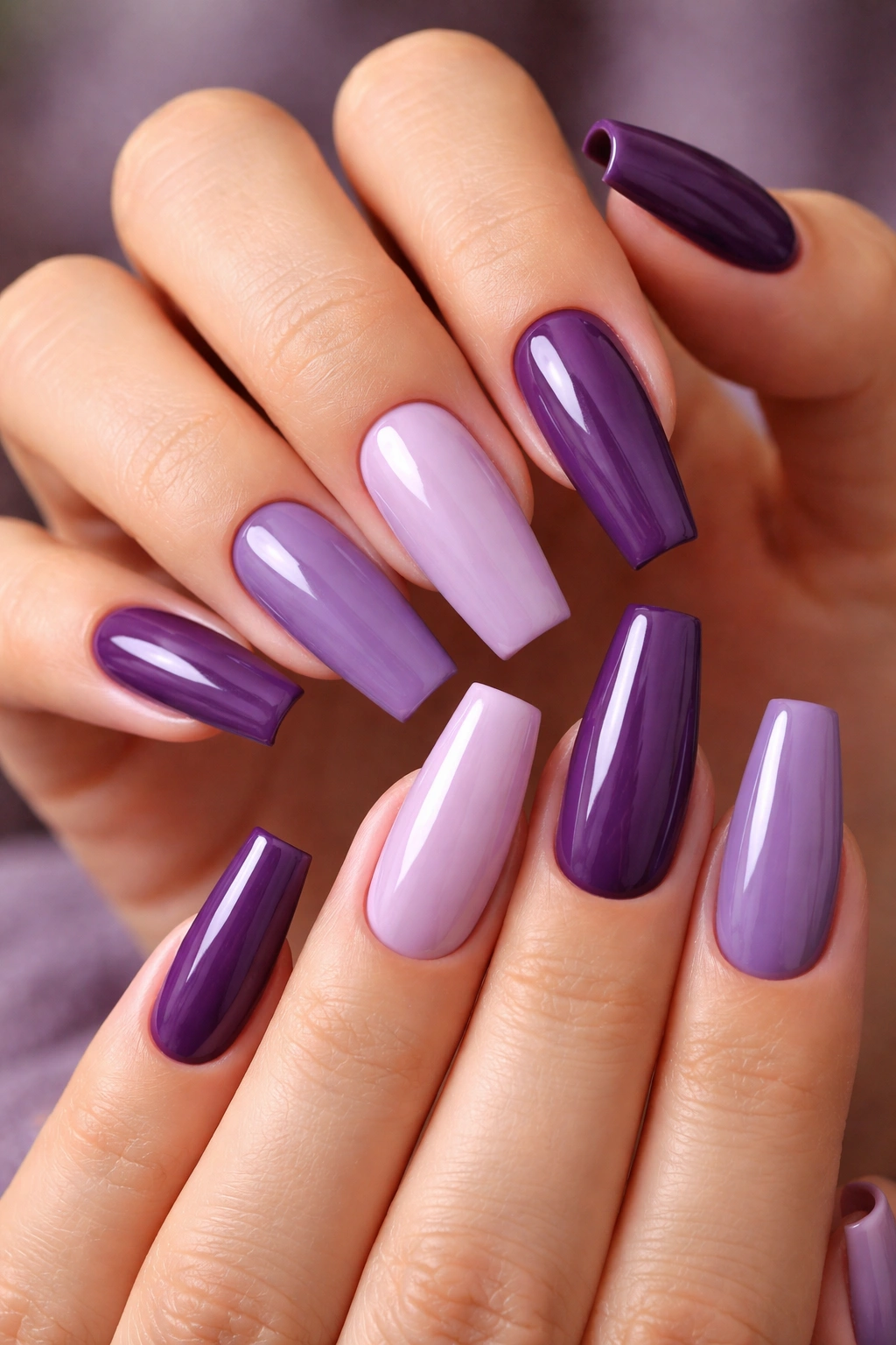 Hands with a cohesive purple coffin nail set in a mix-and-match style