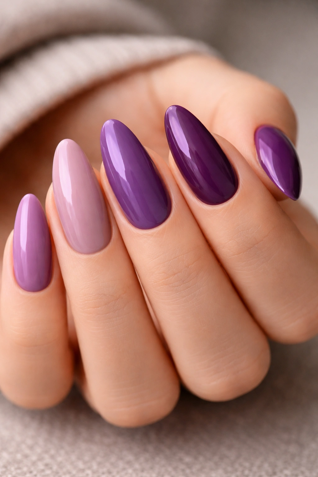 Almond nails with five purple shades arranged in a skittle manicure.