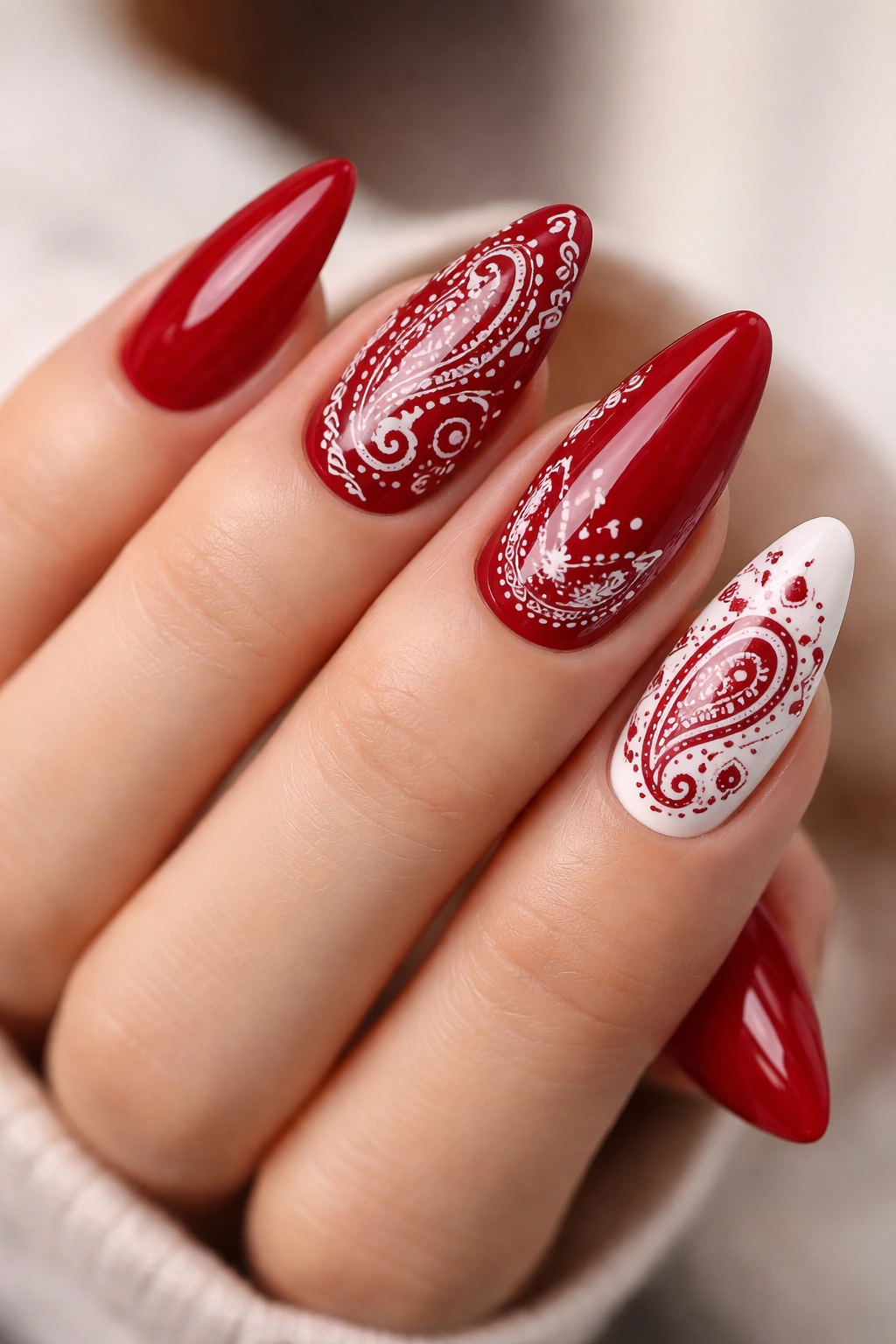 Close-up of almond nails with red bandana paisley pattern