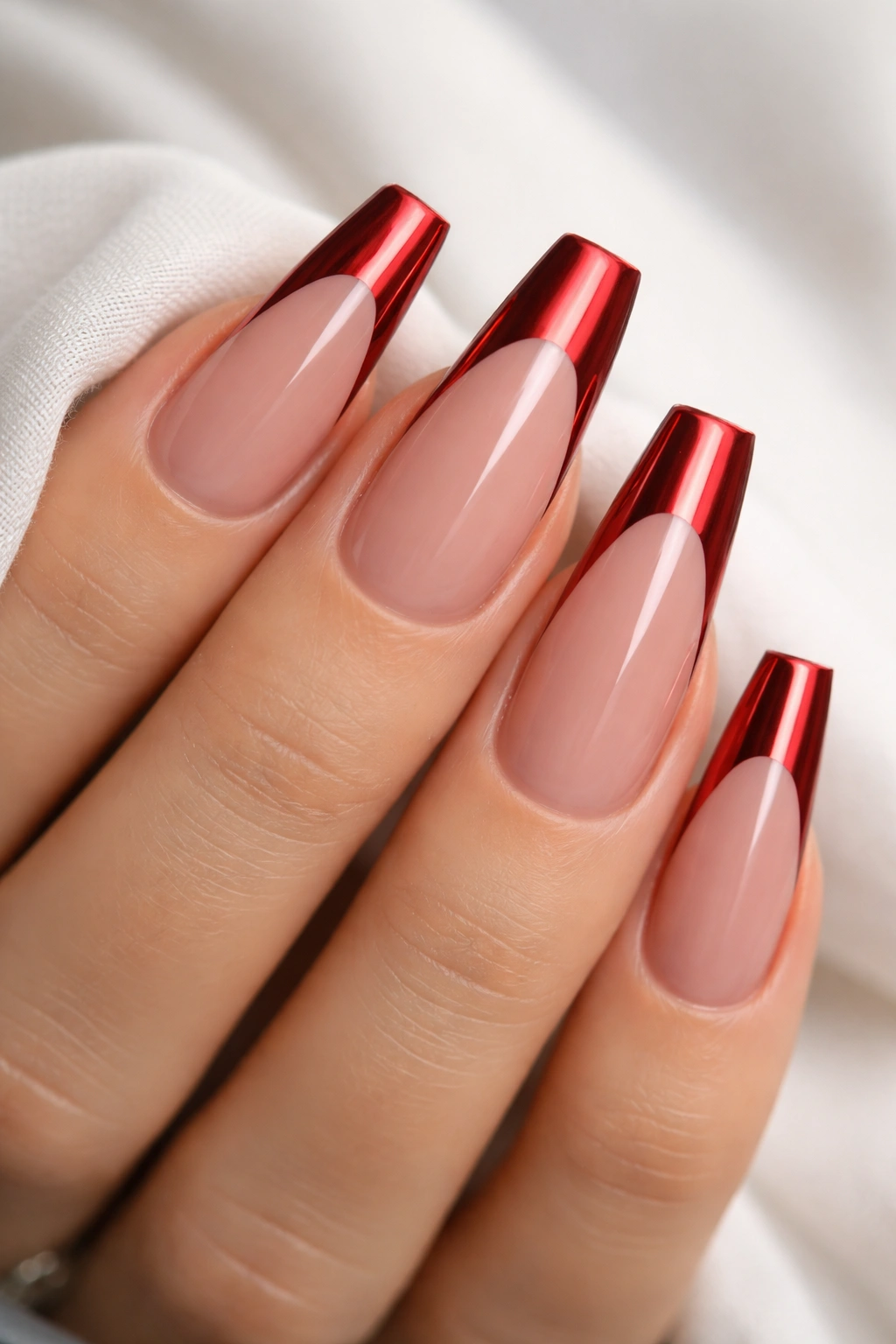 Close-up of red chrome French tips on coffin nails with sheer nude base
