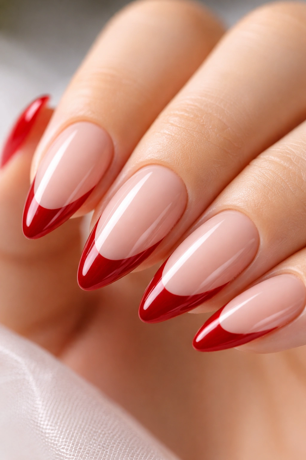 Almond fingernail with cherry red French tip on nude base.