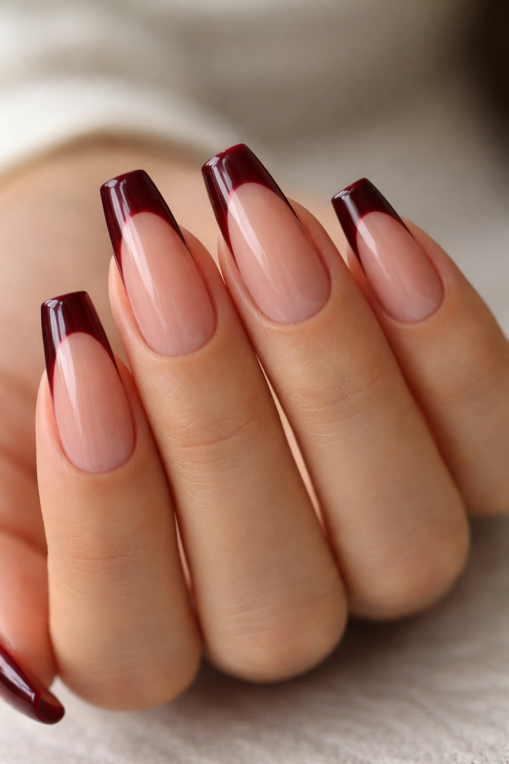 Close-up of medium coffin nails with burgundy wine tips on a nude base