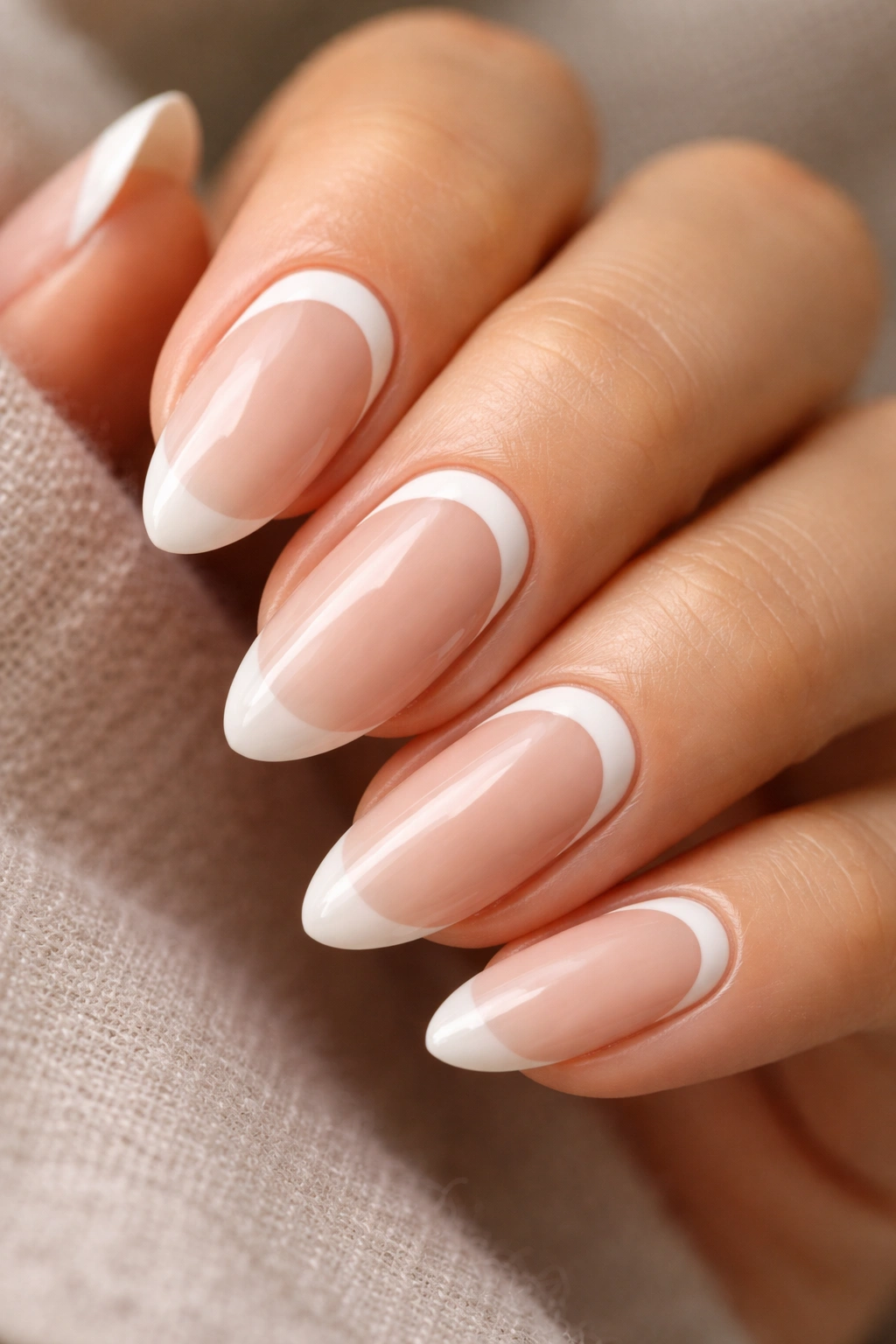 Almond nails with white reverse French arc near the cuticle on a nude base