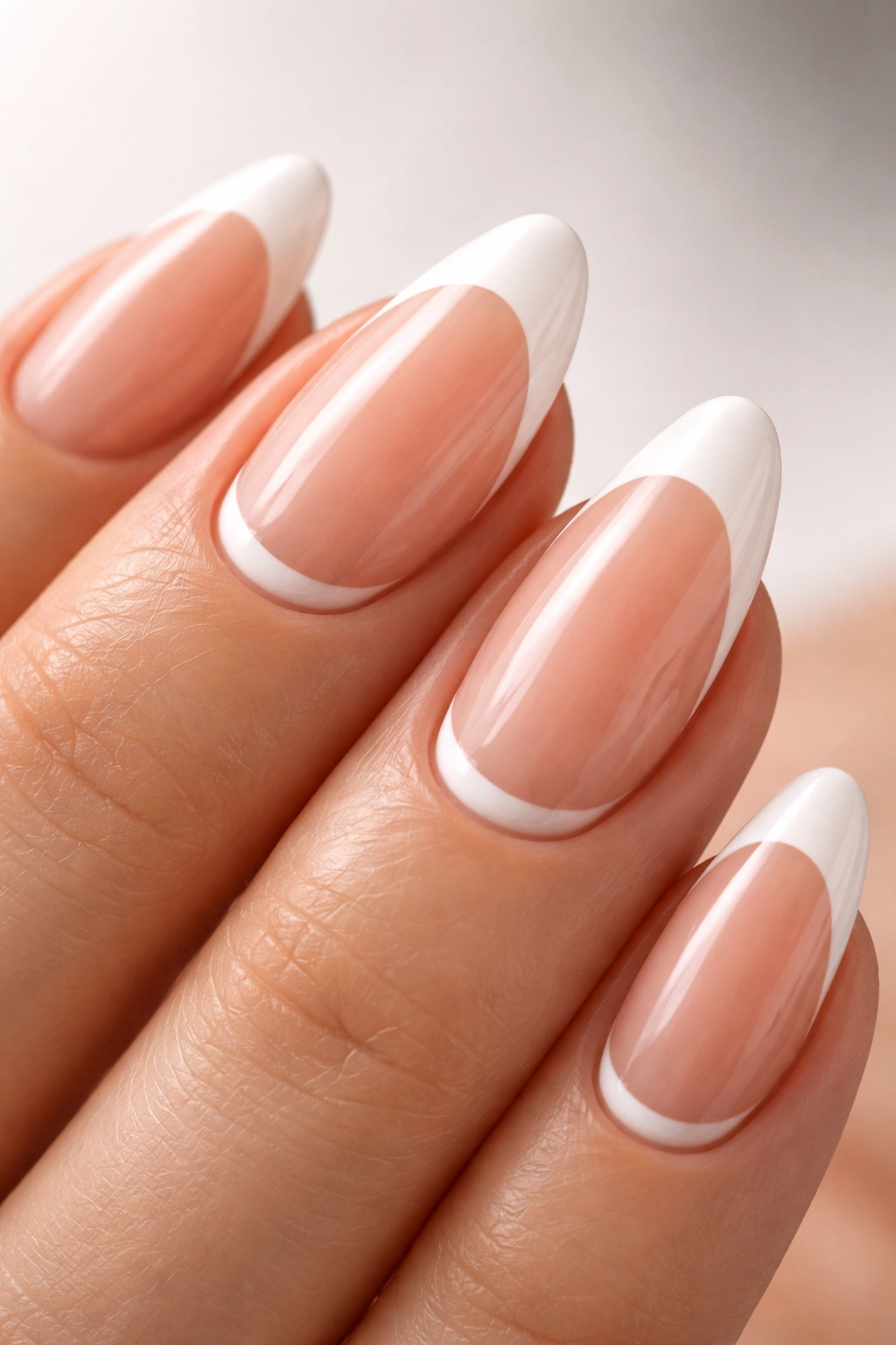 Almond nails showing a reverse French half-moon at the cuticle on nude base