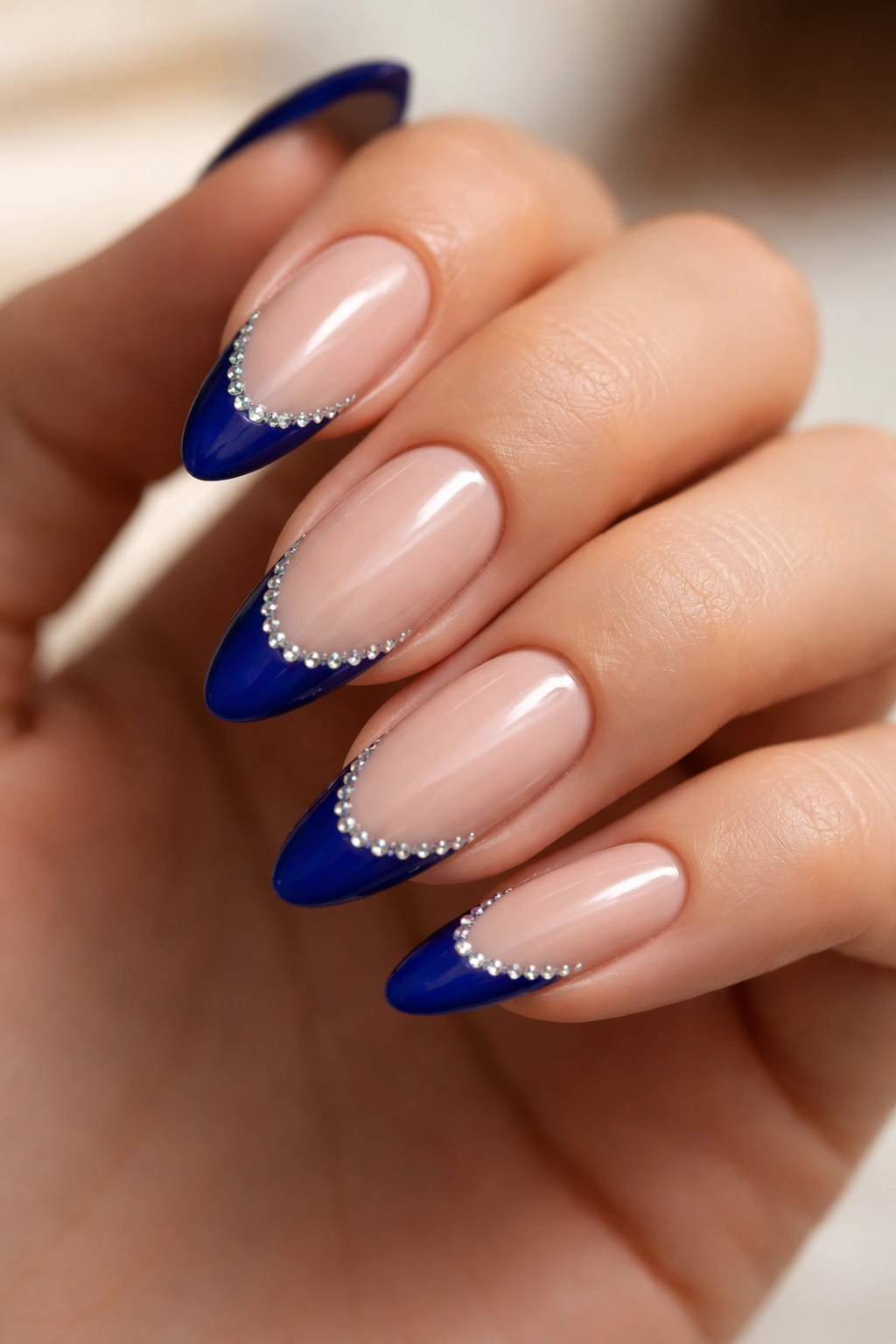 Rhinestone blue French tips on almond nails with sparkle.