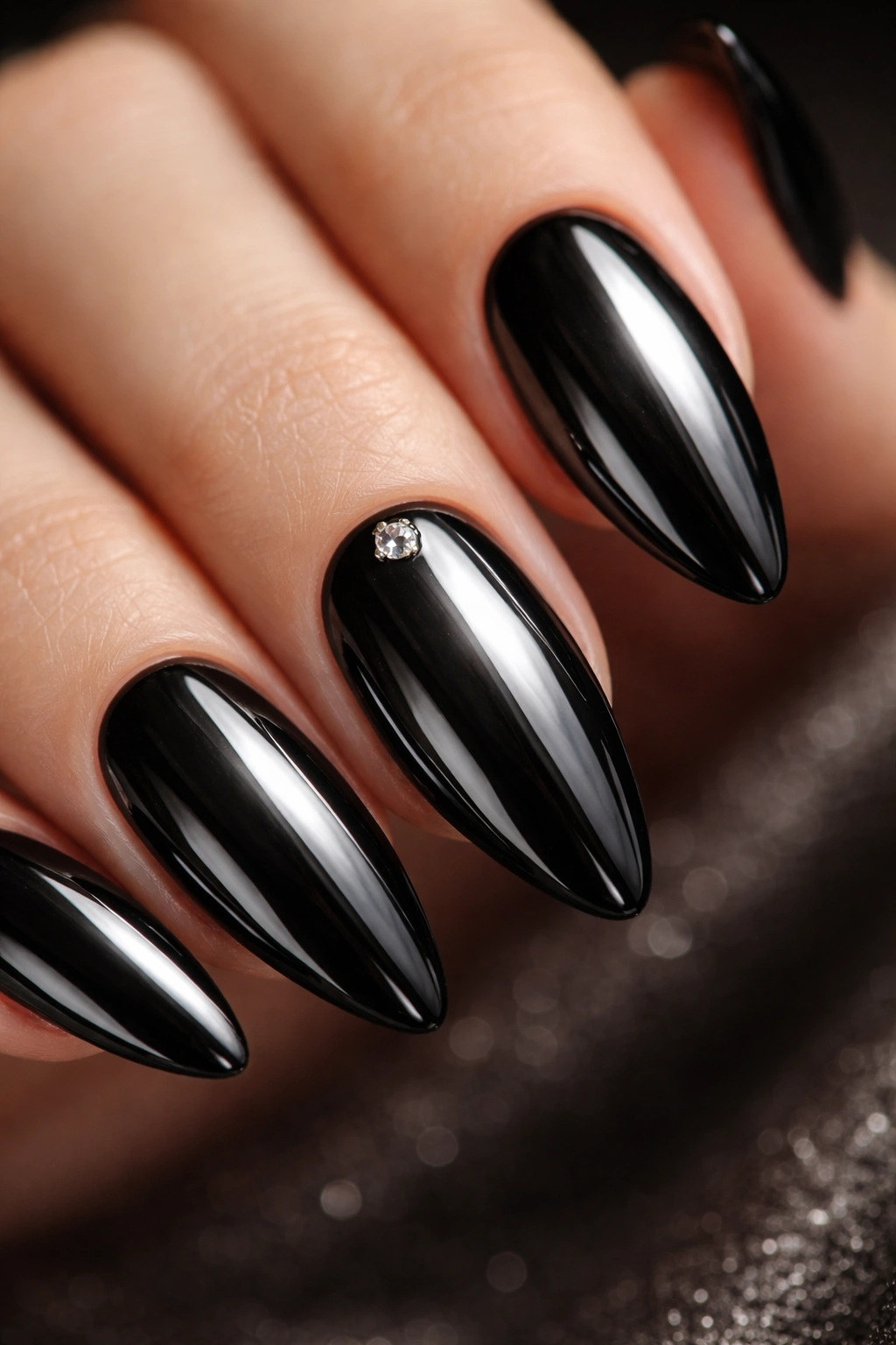 Almond nails in black chrome with a single rhinestone accent