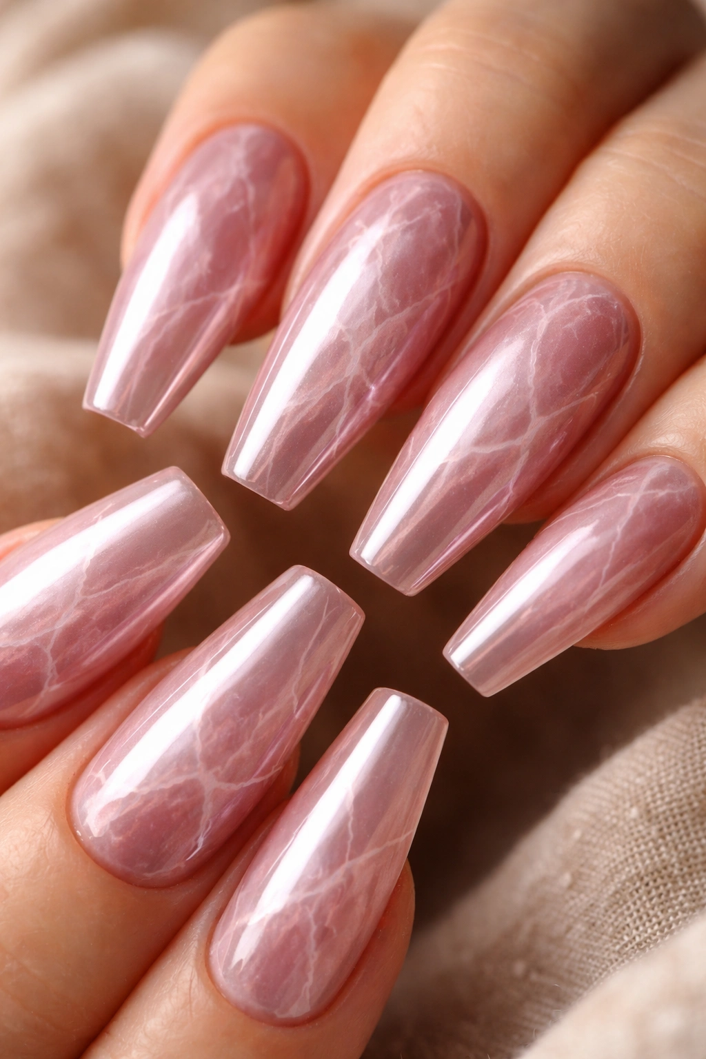 Close-up of rose quartz chrome coffin nails with soft white veining
