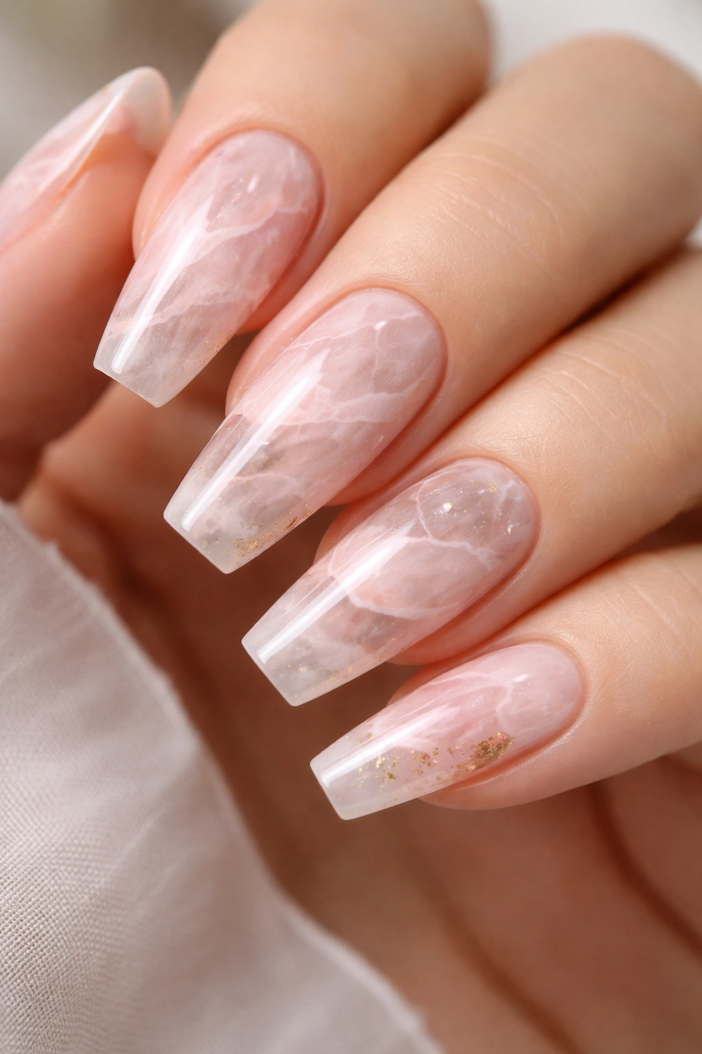 Close-up of Rose Quartz Marble Coffin Nails with translucent blush base, white veining, and gold flecks.