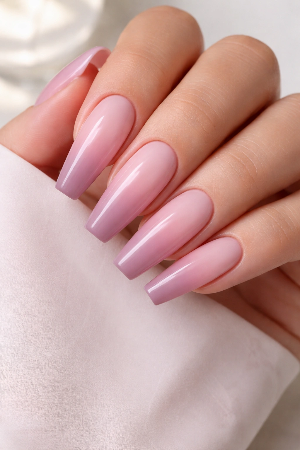 Close-up of rose quartz pink to mauve ombre coffin nails in soft daylight
