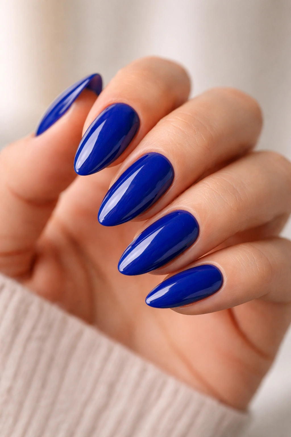 Close-up of almond nails painted in high-gloss royal blue