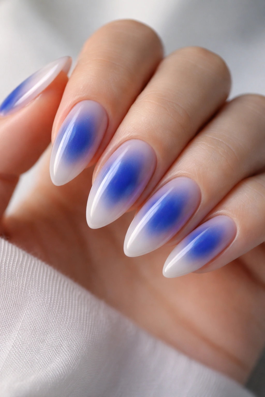 Almond nails with royal blue aura centered on milky base