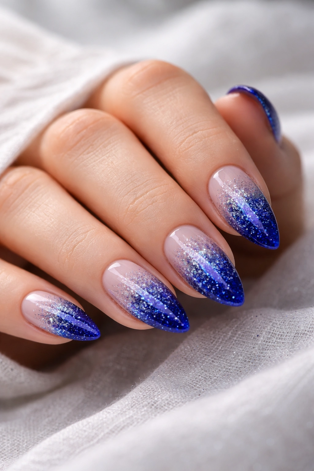 Almond nails with royal blue base and glitter gradient tips