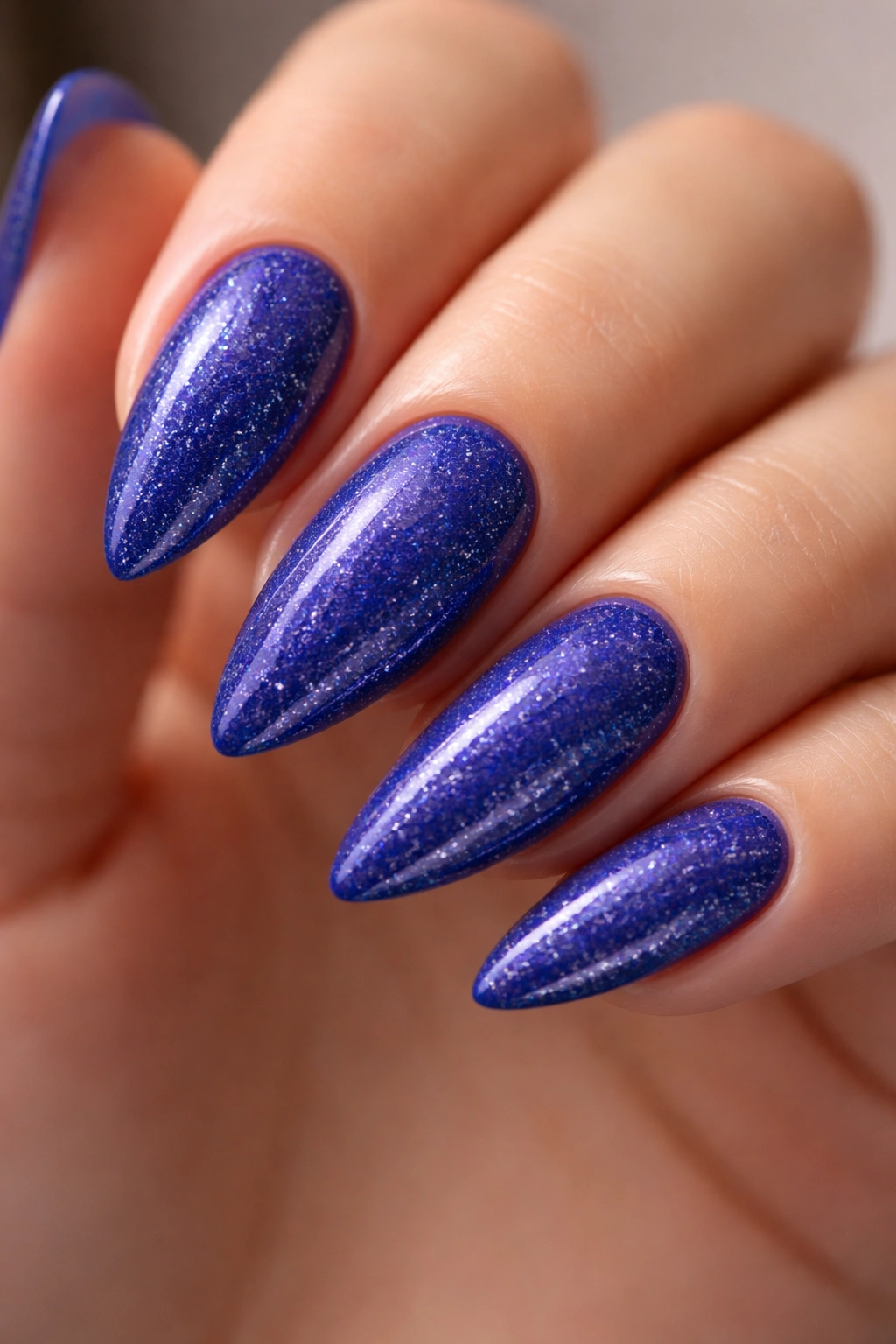 Almond nails with royal blue color and fine silver glitter