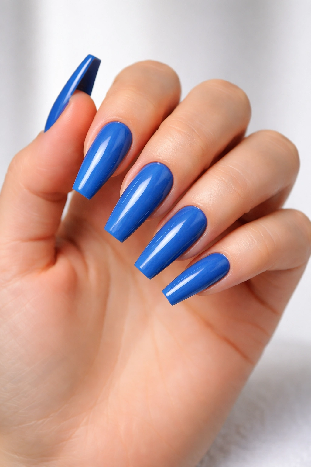 Neatly shaped coffin nails painted blue with clean, polished finish