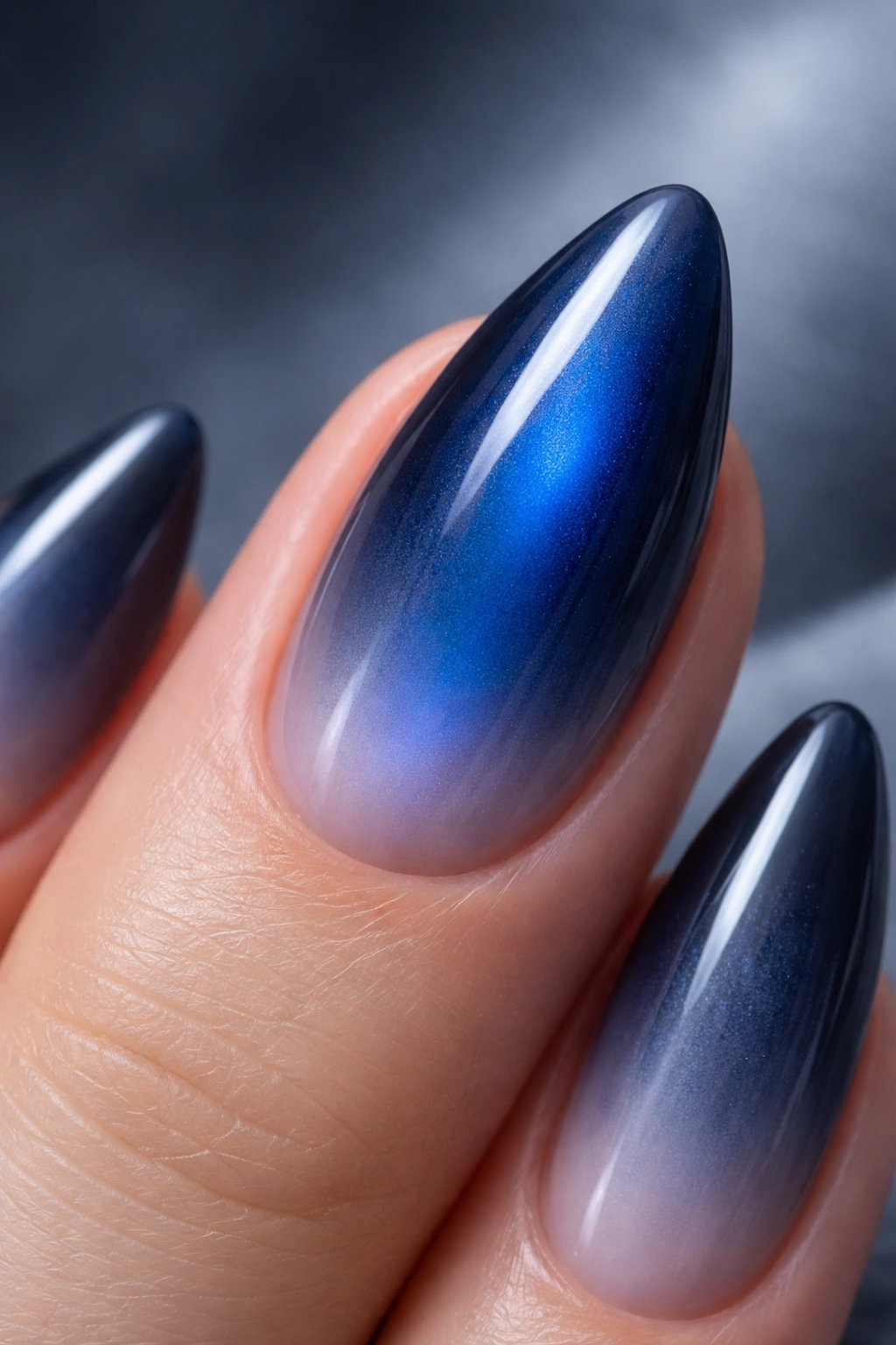Almond nail with sapphire blue center fading to smoky blue-gray edge.