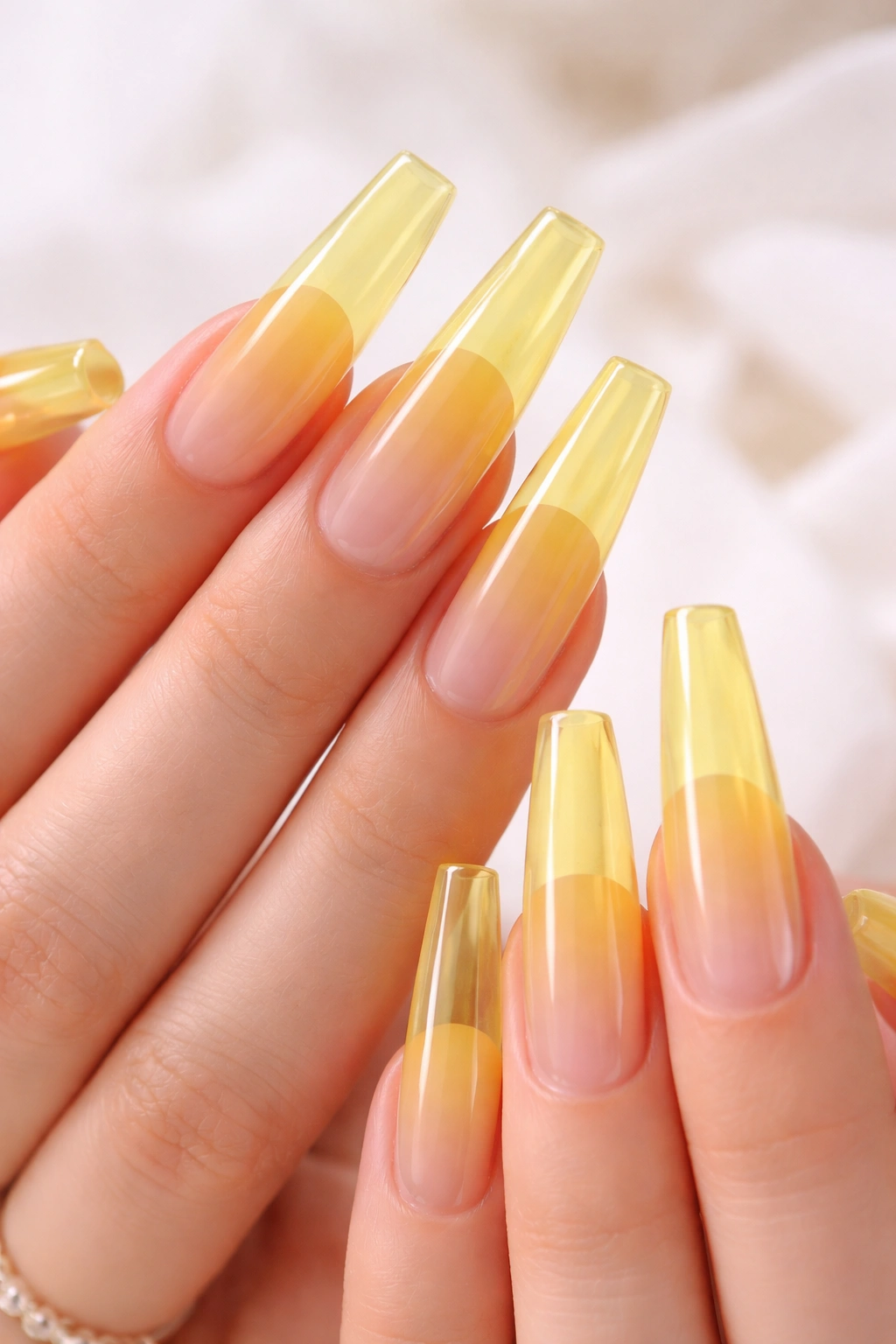 Close-up of sheer yellow jelly coffin nails with translucent candy-glass finish