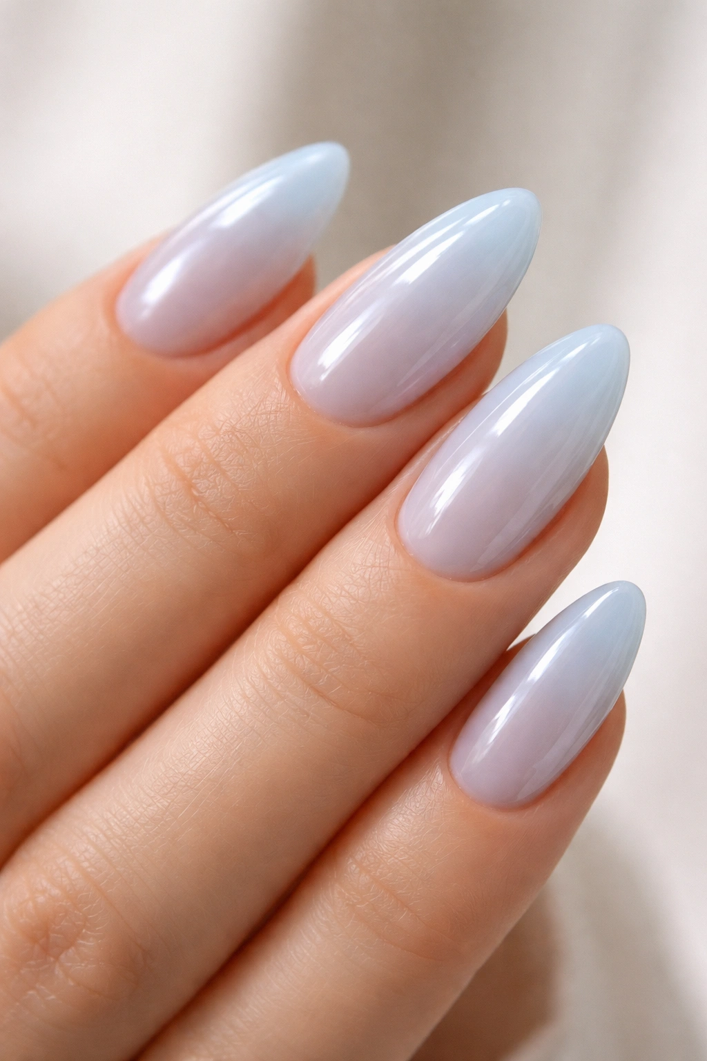 Close-up of sheer pastel blue almond nails with glassy finish