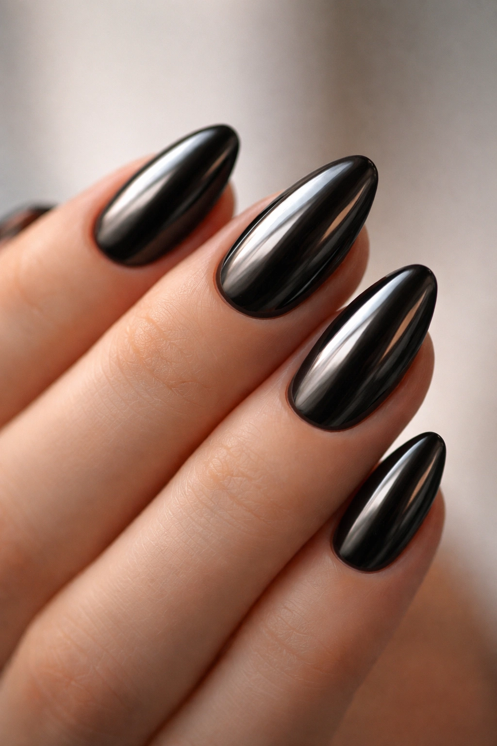Close-up of short almond nails in black chrome finish