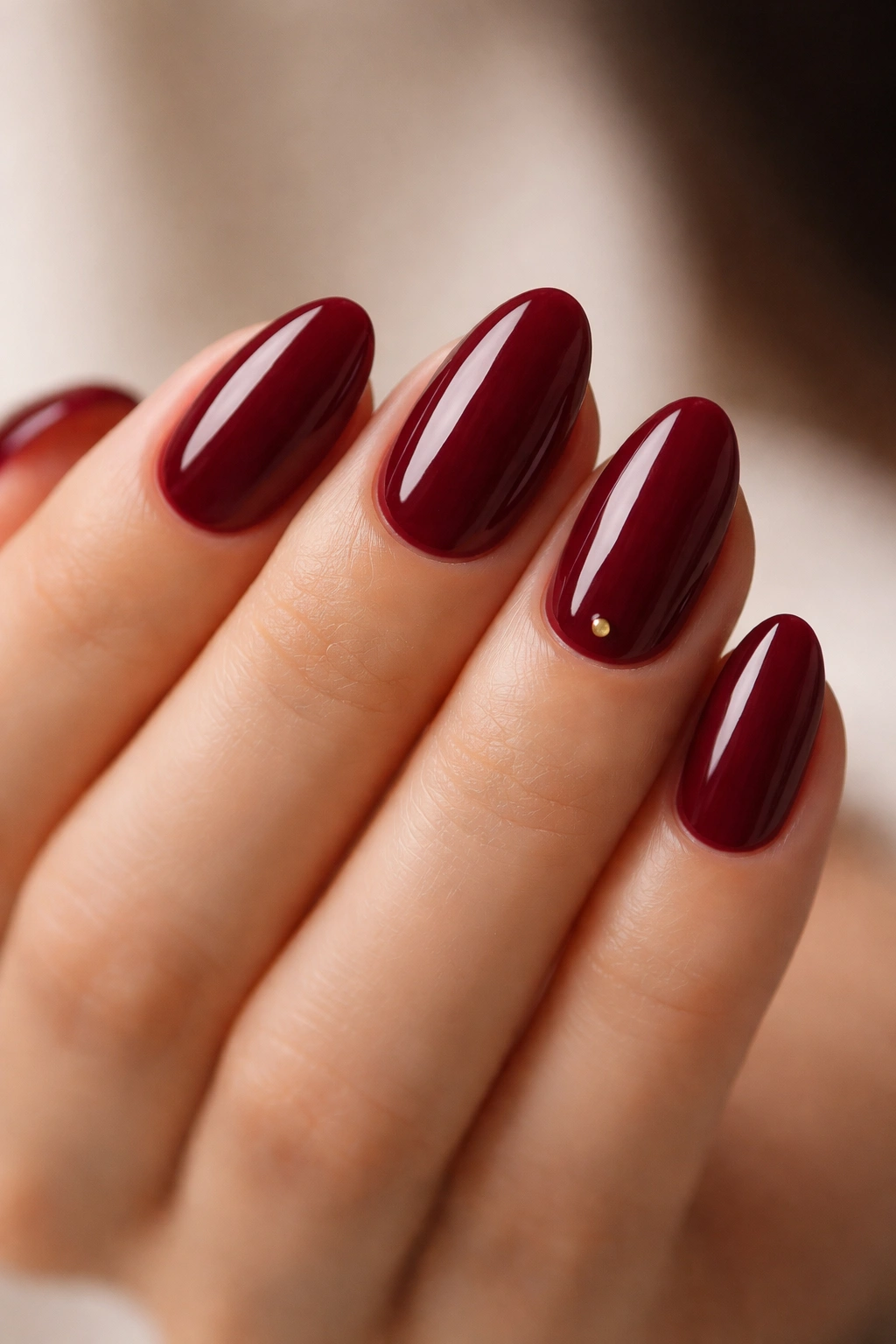 Short almond nails in maroon with a tiny micro detail near the cuticle