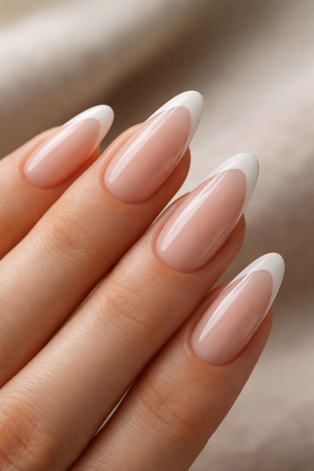 Close-up of almond nail with diagonal white French tip on nude base