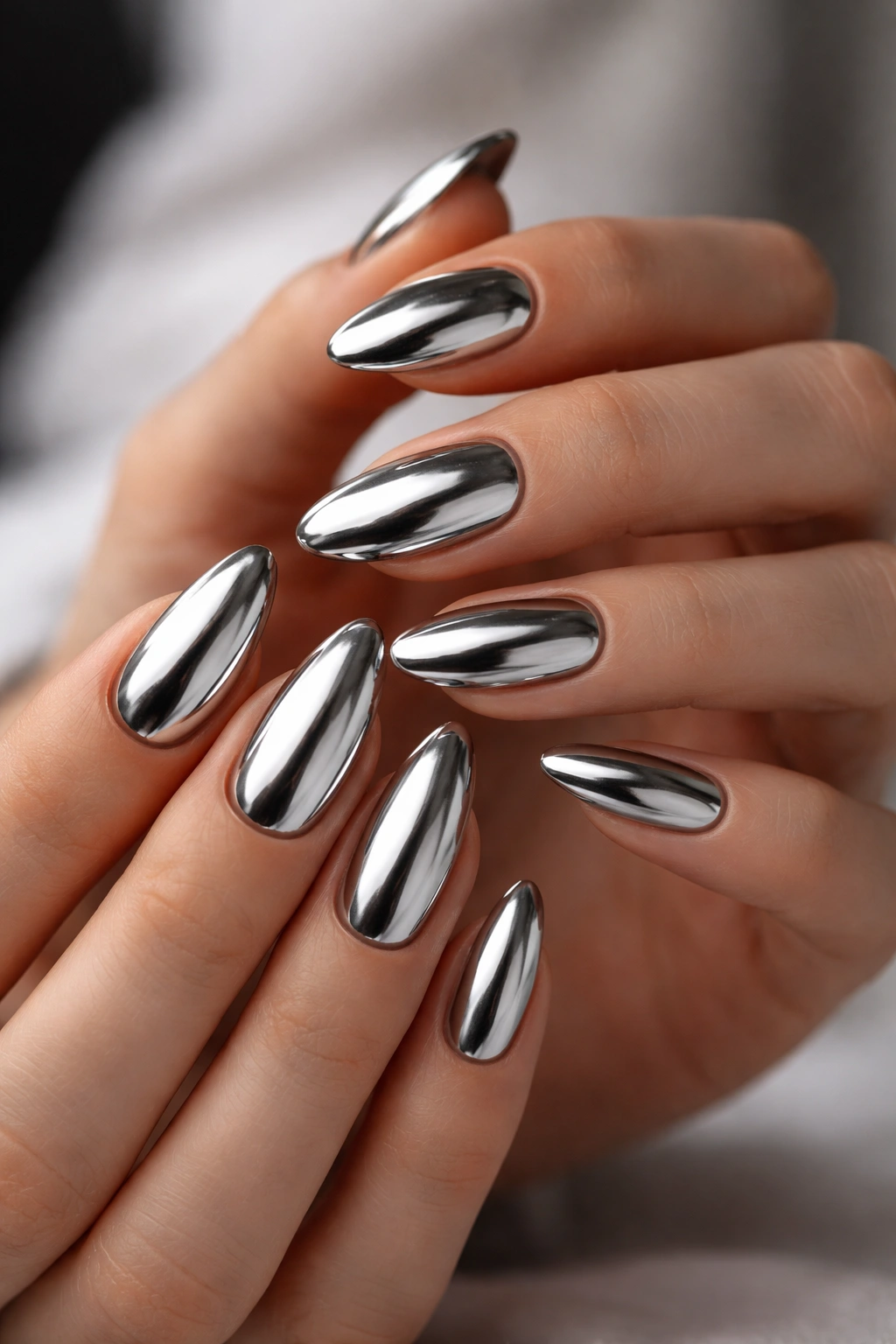 Close-up of silver mirror chrome almond nails on a black base