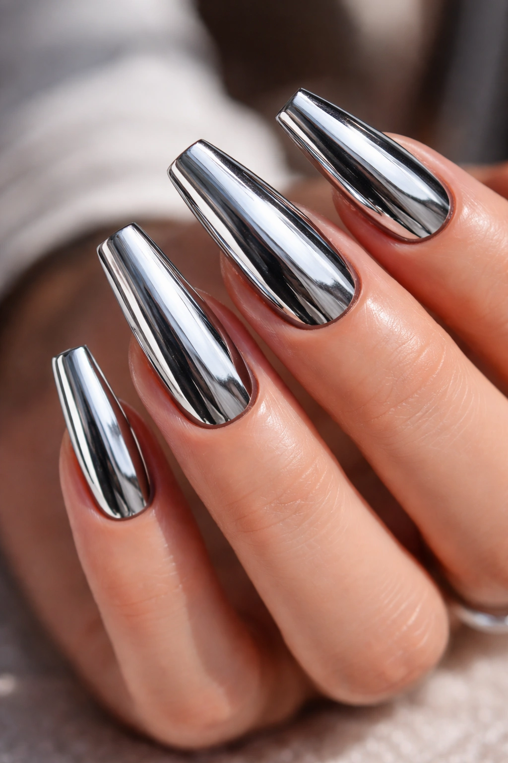 Close-up of coffin nails with mirror silver chrome finish reflecting light on a dark base